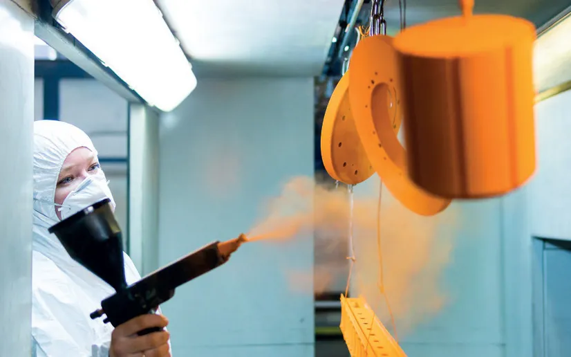 Operator spraying Ritver powder coating onto a metal part